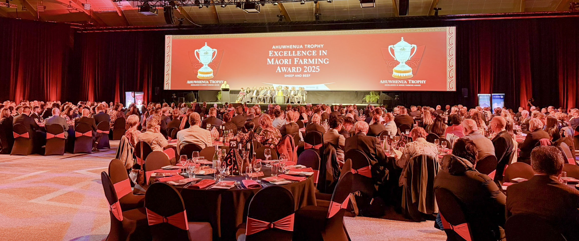Large awards event with a panoramic screen, stage lighting and a full audience