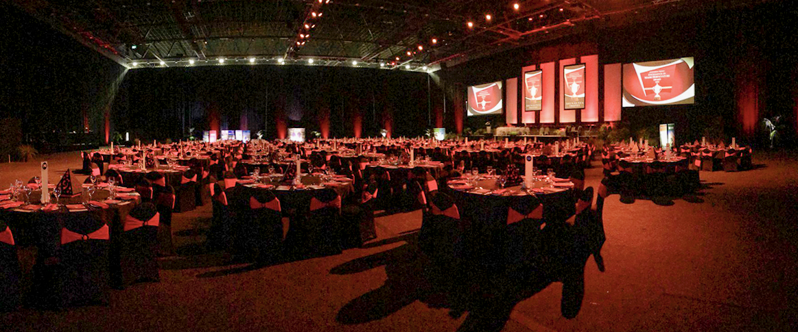 Large banquet room with projection screens, stage lighting and event seating